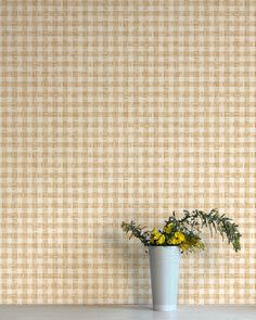 a potted plant with yellow flowers in front of a tan and white checkered wall