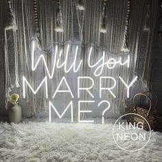 a white shaggy rug with the words will you marry me? written in neon lights