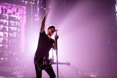 a man standing on top of a stage with his arms in the air while holding a microphone