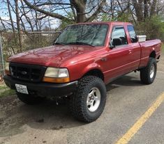 a red pick up truck is parked on the side of the road