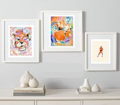 three framed art pieces on a wall above a dresser