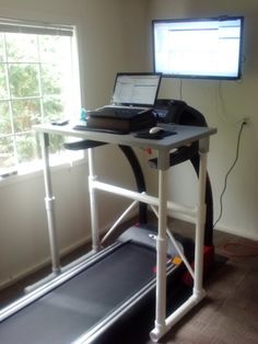 a treadmill with a laptop on top of it in front of a large window