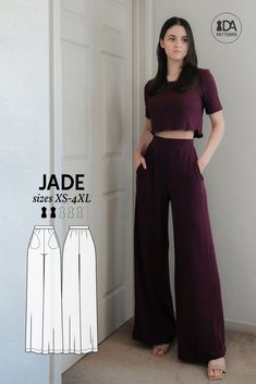 a woman standing in front of a door wearing wide legged pants and cropped top