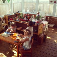 three children sitting at a table playing with toys