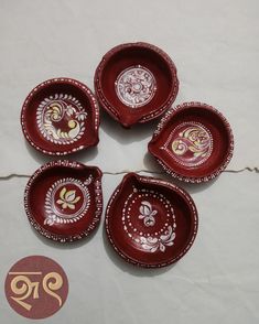 five red plates with designs on them sitting on a table