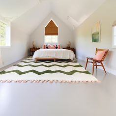 a bedroom with a bed, chair and rug in it