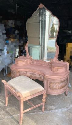 a pink vanity with mirror and stool in front of it