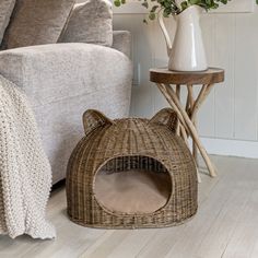 a cat bed sitting on top of a wooden floor next to a couch and table