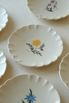 four plates with flowers painted on them sitting on a table