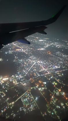 an aerial view of the city lights at night from inside an airplane window, looking down