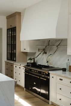 a kitchen with marble counter tops and white cabinets, along with an oven in the center