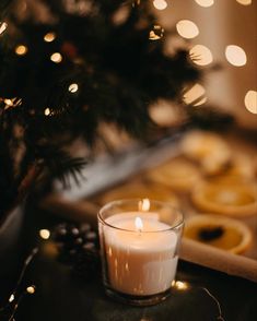 a lit candle sitting on top of a table next to cookies and a christmas tree