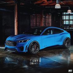 a blue car is parked in an empty garage with lights on and dark floors,