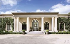 a large house with columns and arches on the front door is surrounded by greenery