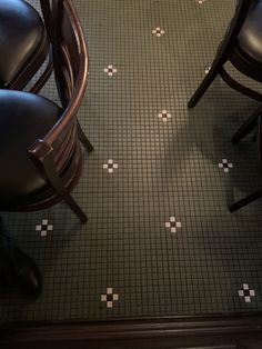 two chairs sitting next to each other in front of a tiled floor with white dots on it