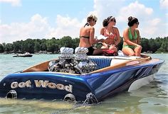 three women sitting on the back of a blue boat