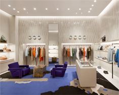 the inside of a clothing store with blue chairs