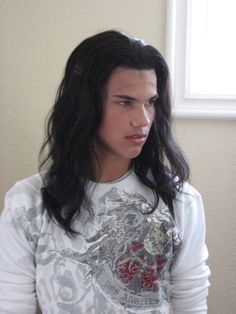 a man with long black hair wearing a white shirt