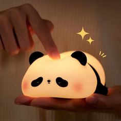 a person is holding a small light that looks like a panda bear's head