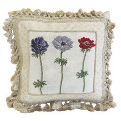 an embroidered pillow with three flowers on the front and one flower in the middle, sitting on