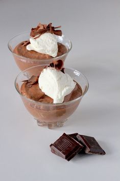 two desserts with chocolate and whipped cream in small glass bowls next to one another