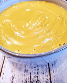 a bowl filled with yellow sauce sitting on top of a wooden table