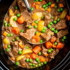 a ladle full of stew with peas and carrots on the side, in a slow cooker