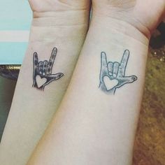 two people with matching tattoos on their arms holding hands up to each other, one has a heart in the middle