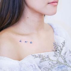 a woman's chest with three birds on it and flowers in the foreground