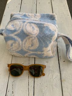 a pair of sunglasses sitting on top of a wooden table next to a blue and white bag