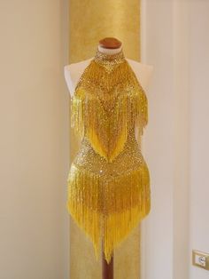 a mannequin is dressed in gold sequins and stands next to a lamp