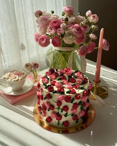 there is a cake with pink flowers on it and a candle next to the cake