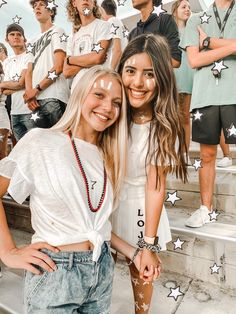 two young women standing next to each other in front of a group of people with their faces painted