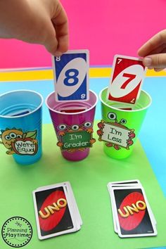 someone is placing cards into cups on a table with numbers and pictures around them,