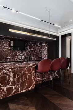 a kitchen with marble counter tops and red chairs