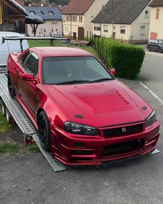 a red car is being loaded onto a flatbed trailer