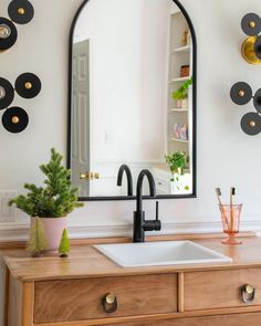 a bathroom sink sitting under a mirror next to a wooden counter top with potted plants on it