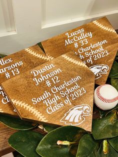 three graduation caps on top of green leaves with a baseball in the middle and other decorations around them