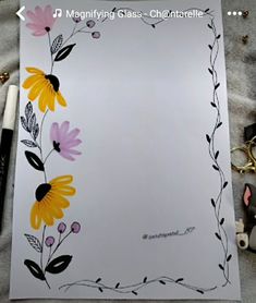 a sheet of paper with flowers painted on it and some pens next to it,