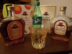 three bottles of liquor sitting on top of a table next to a glass filled with liquid