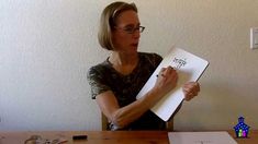 a woman sitting at a table holding a piece of paper