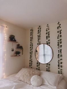 a bedroom with white bedding and plants on the wall, along with a round mirror