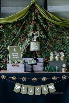 a table topped with cake and cupcakes next to a wall covered in leaves