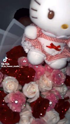 a hello kitty teddy bear sitting on top of roses