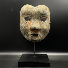 an old mask is displayed on a stand