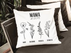 a pillow with flowers on it sitting on a couch next to some pillows and plants