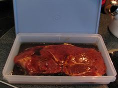 a plastic container filled with meat sitting on top of a counter next to a stove