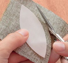 someone cutting paper with scissors on top of a piece of cloth that has been folded