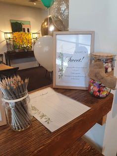 a table topped with lots of pencils next to a vase filled with flowers and balloons