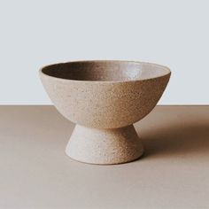 a white bowl sitting on top of a table next to a gray wall and floor